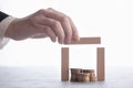 Hand folds a wooden house made of blocks with coins inside, the concept of capital protection and insurance agent services Royalty Free Stock Photo