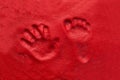 Hand and foot print of child made on red background