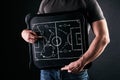 Hand of a football or soccer play coach drawing a tactics of football game with white chalk on blackboard at changing room during