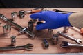 The hand of the foreman in a blue work glove takes a wrench from the work table Royalty Free Stock Photo