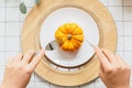 Hand with fork and knife cutting yellow pumpkin on white plate Royalty Free Stock Photo
