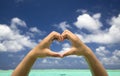 Hand forming a heart on beach