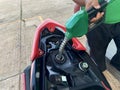 Hand fuel nozzle in pouring to motorcycle at gas station