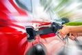 Female Hand with fuel pistol and red car with motion blur effect Royalty Free Stock Photo