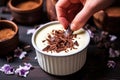 hand garnishing almond milk pudding with chocolate shavings