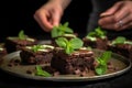 hand garnishing brownies with fresh mint leaves
