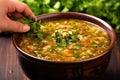 hand garnishing hot and sour soup with fresh coriander