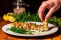 hand garnishing a plate of grilled calamari with parsley