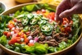 hand garnishing taco salad with jalapeno slices