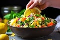 hand garnishing vegetable couscous salad with lemon wedges