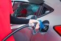 Hand of gas station attendant holding a fuel petrol pump nozzle against for filling up the car with petrol at gas station Royalty Free Stock Photo