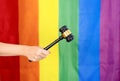 hand of gay pride holding wood gavel or judge hammer background lgbtq rainbow flag Royalty Free Stock Photo