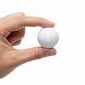 A hand gently holding a smooth white spherical object against a plain background Royalty Free Stock Photo
