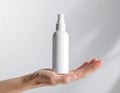 Hand holding blank white spray bottle on a plain white background image photo Royalty Free Stock Photo