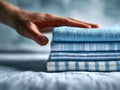 Hand gently touching a neatly folded stack of blue and white striped and checkered textiles on a soft surface with a blurred Royalty Free Stock Photo