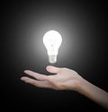 Hand gesture holding floating light bulb with light on dark background. Conceptual thinking new idea. Concept idea. Royalty Free Stock Photo