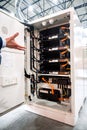 Hand gestures at an open high-tech energy storage system cabinet, revealing rows of advanced power modules and intricate wiring. Royalty Free Stock Photo
