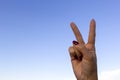 Hand gesturing peace sign or victory on blue sky background Royalty Free Stock Photo