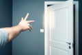 Hand gesturing toward open white door in blue room Royalty Free Stock Photo