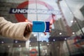 Hand of a girl holding an Oyster card outside the entrance of the underground. The card allows access to the underground in London