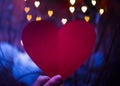 Hand of a girl holding paper red heart, heart bokeh Royalty Free Stock Photo