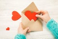 Hand of girl writing love letter on Saint Valentines Day. Handmade postcard with red heart shaped figure. 14 February holiday Royalty Free Stock Photo