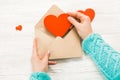 Hand of girl writing love letter on Saint Valentines Day. Handmade postcard with red heart shaped figure. 14 February holiday Royalty Free Stock Photo