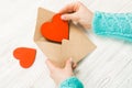 Hand of girl writing love letter on Saint Valentines Day. Handmade postcard with red heart shaped figure. 14 February holiday Royalty Free Stock Photo