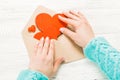 Hand of girl writing love letter on Saint Valentines Day. Handmade postcard with red heart shaped figure. 14 February holiday Royalty Free Stock Photo