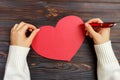 Hand of girl writing love letter on Valentine Day. Handmade red heart postcard. Woman write on postcard for 14 February holiday ce Royalty Free Stock Photo