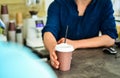 Hand gives cup to client visitor. Man receive drink at bar counter. Cappuccino or cacao with straw. Served in paper cup Royalty Free Stock Photo