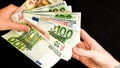 Euro currency, european uninon money, hand giving euros cash on the black background Royalty Free Stock Photo