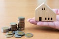 Hand giving house mock up beside of increasing coins stack on wooden table. Successful investment for home or real estate Royalty Free Stock Photo