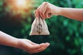 hand giving money bag to another people on green background with sunrise Royalty Free Stock Photo
