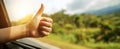 The hand giving a thumbs up from a car window during a scenic drive. AI generated image Royalty Free Stock Photo