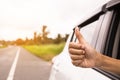 Hand giving a thumbs up sign throw the window of a car parked near the roads.The symbol of a hand raised for help.