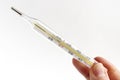 Hand with glass mercury thermometer with celsius degree. Thermometer close-up on white background. Health temperature concept