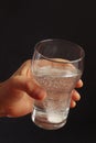 Hand with a glass of water and effervescent tablet on dark background. Royalty Free Stock Photo