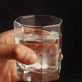 Hand with a glass of water and soluble tablet on dark background. Royalty Free Stock Photo