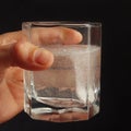 Hand with a glass of water and soluble tablet from headache on dark background. Royalty Free Stock Photo