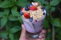 Hand with glass with yogurt, cereals, strawberries and blueberries - closeup