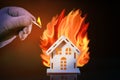 Hand in glove with a burning match sets fire to the house model of matches, risk, property Insurance. House And Fire.