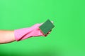 Hand with glove hoding scourer on green background Royalty Free Stock Photo