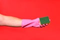 Hand with glove hoding scourer on red background Royalty Free Stock Photo