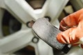 Hand in glove holding invalid brake lining for changed on wheel background