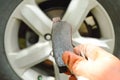 Hand in glove holding invalid brake lining for changed on wheel background