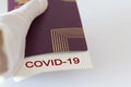 Hand with glove holding Passport and covid-19 note. Concept of Travelling during coronavirus, covid-19 pandemic