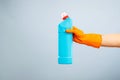 Hand in glove holding a plastic detergent bottle on blue background Royalty Free Stock Photo