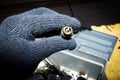 Hand with glove holding spark plug