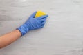 Hand in a glove is holding a yellow sponge and washing a wall. empty space for text Royalty Free Stock Photo